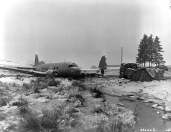 Photo:  SC236662 - The pilot of a C-47 cargo transport crash lands safely after having dropped supplies to elements of the 101st Airborne Division which has successfully repulsed all attempts to capture the besieged city of Bastogne, Belgium. 30 Dec 1944.